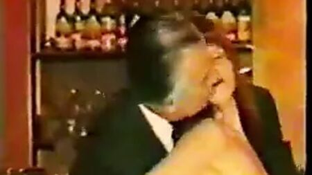 スーツ姿の年配男性が、ツイードを着た大人のバーのウェイトレスにからかわれる